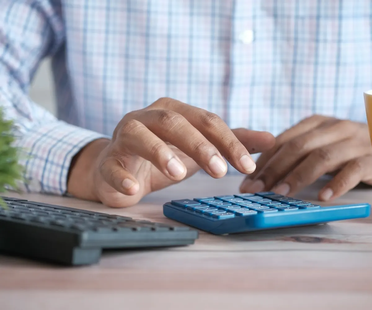 A person working through figures on a desk calculator.