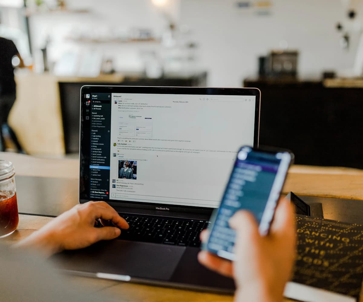 A person comparing a team workspace across laptop and mobile screens.