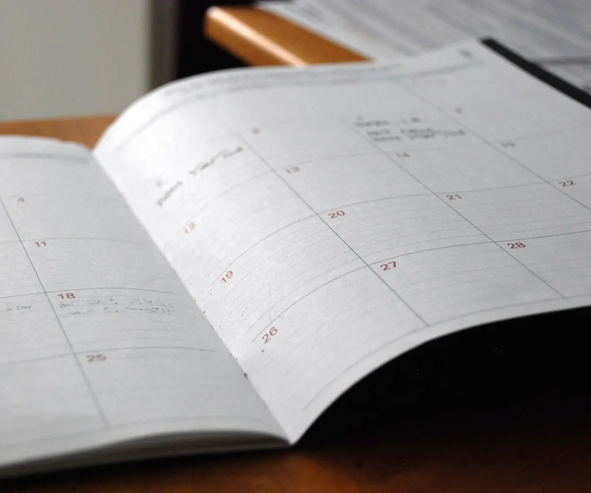 An open monthly planner on a wooden desk.